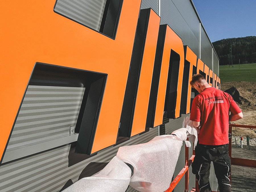 Ein Lehrlinge montiert eine Lichtwerbeanlage, Ausbildung in Werbetechnik in Altenmarkt, Salzburg